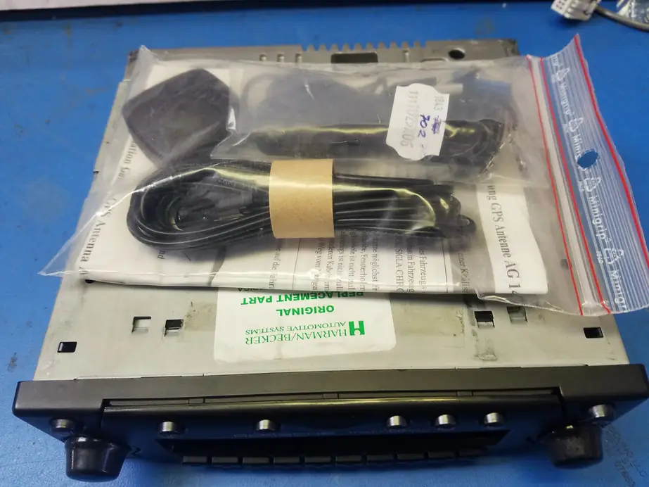 A Porsche PCM unit with a Harman/Becker Automotive Systems original replacement part label on the shop's blue workbench